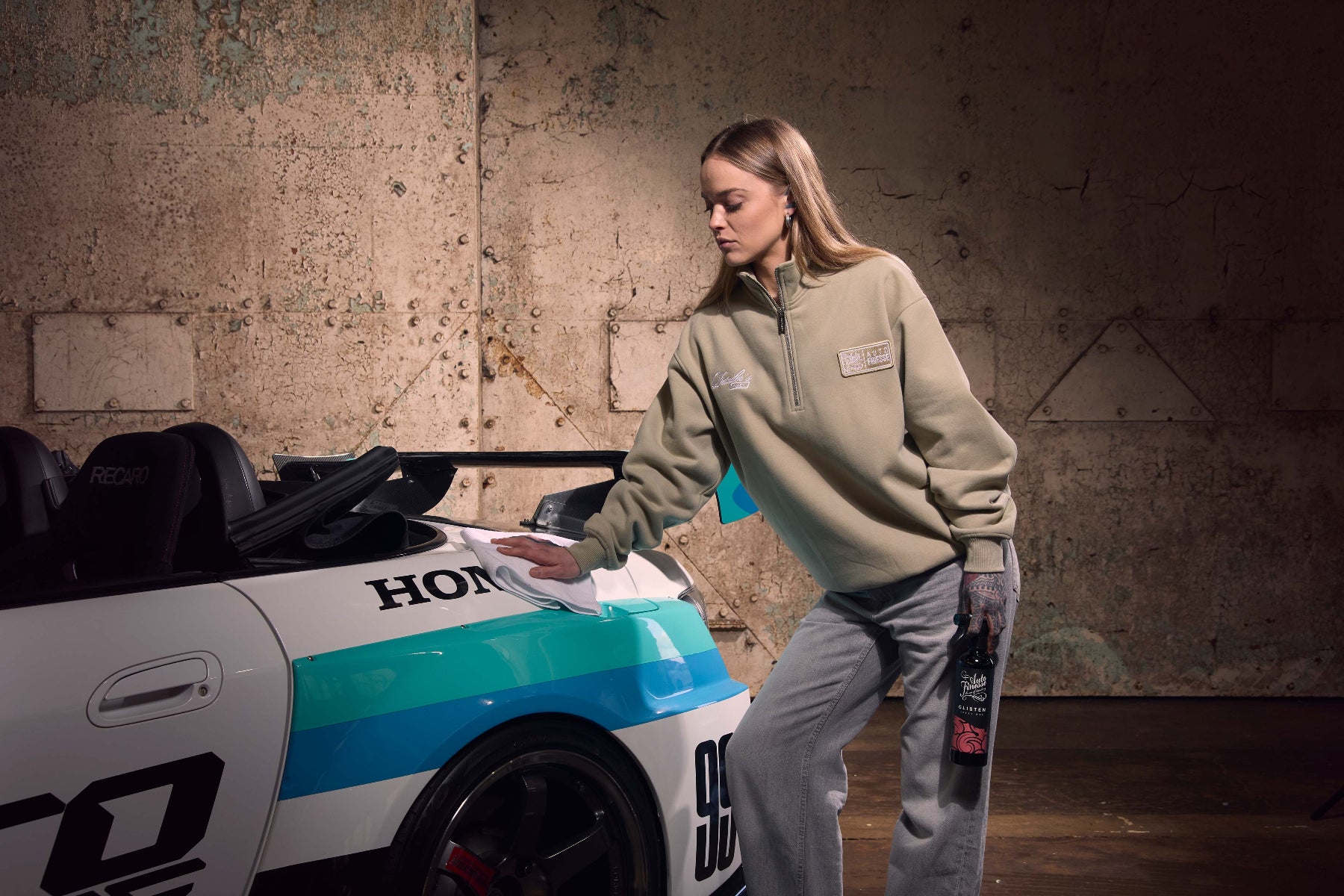 Person cleaning a Honda car with a rag in a garage setting