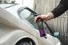 Person holding a car care product spray can next to a white car