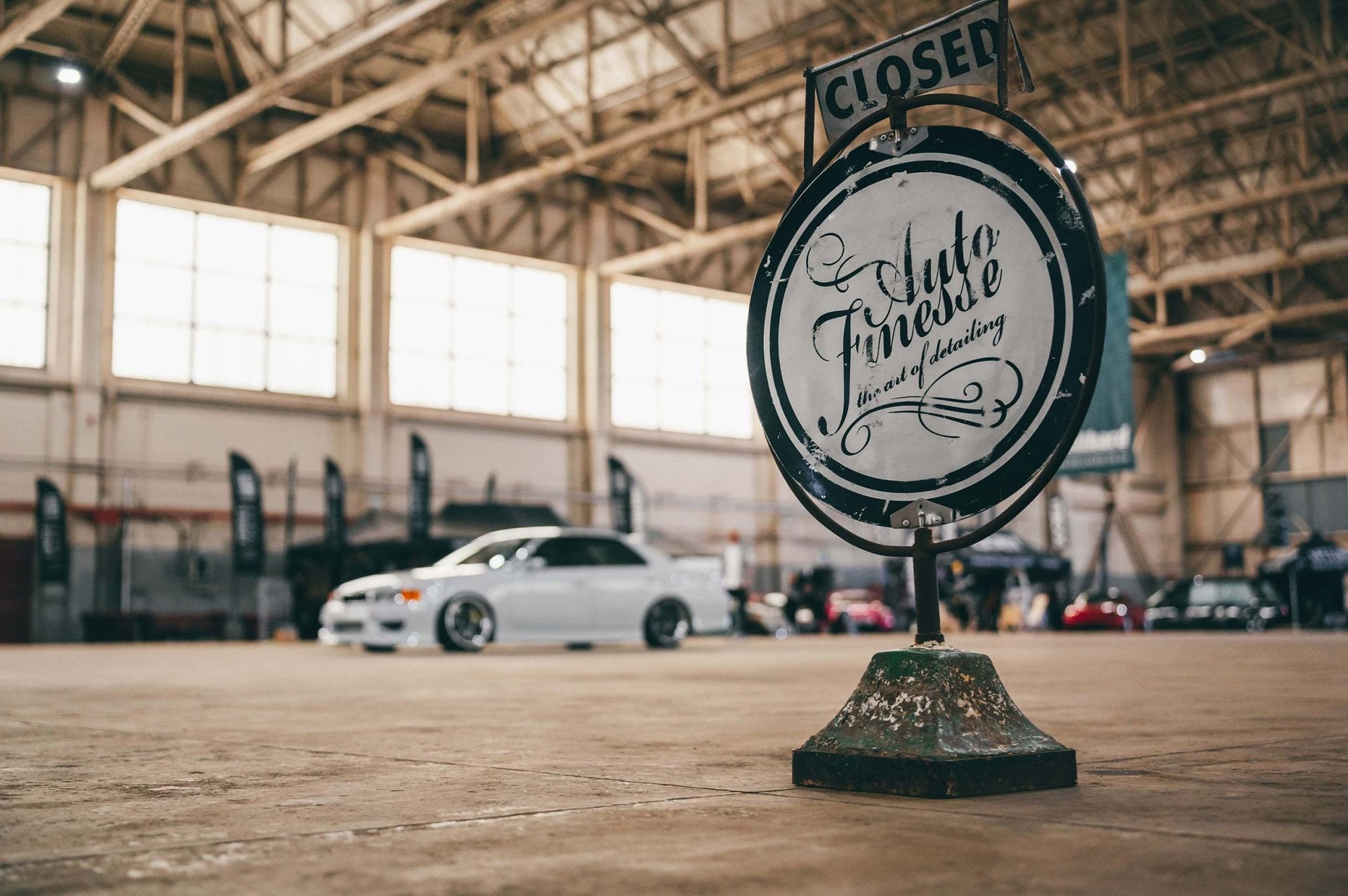 Vintage-style sign in a warehouse setting with cars in the background