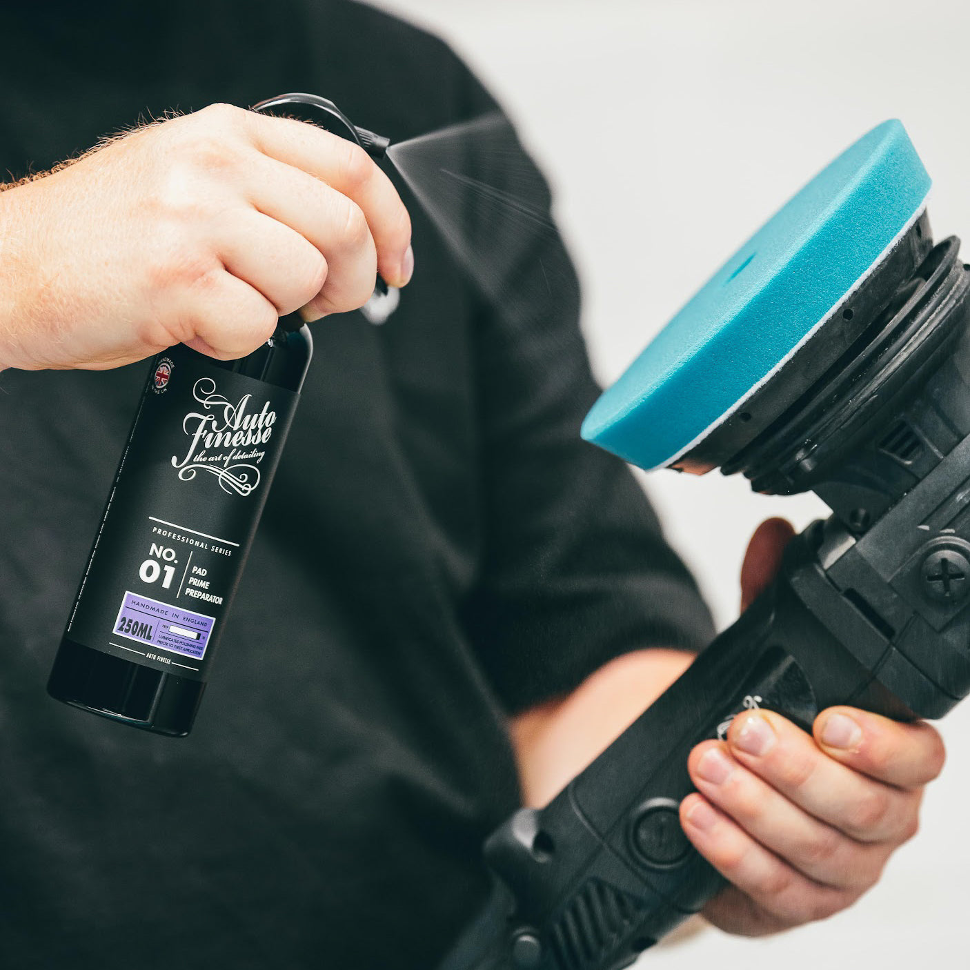 Person holding a car detailing tool and a bottle of 'Auto Fitness' product.