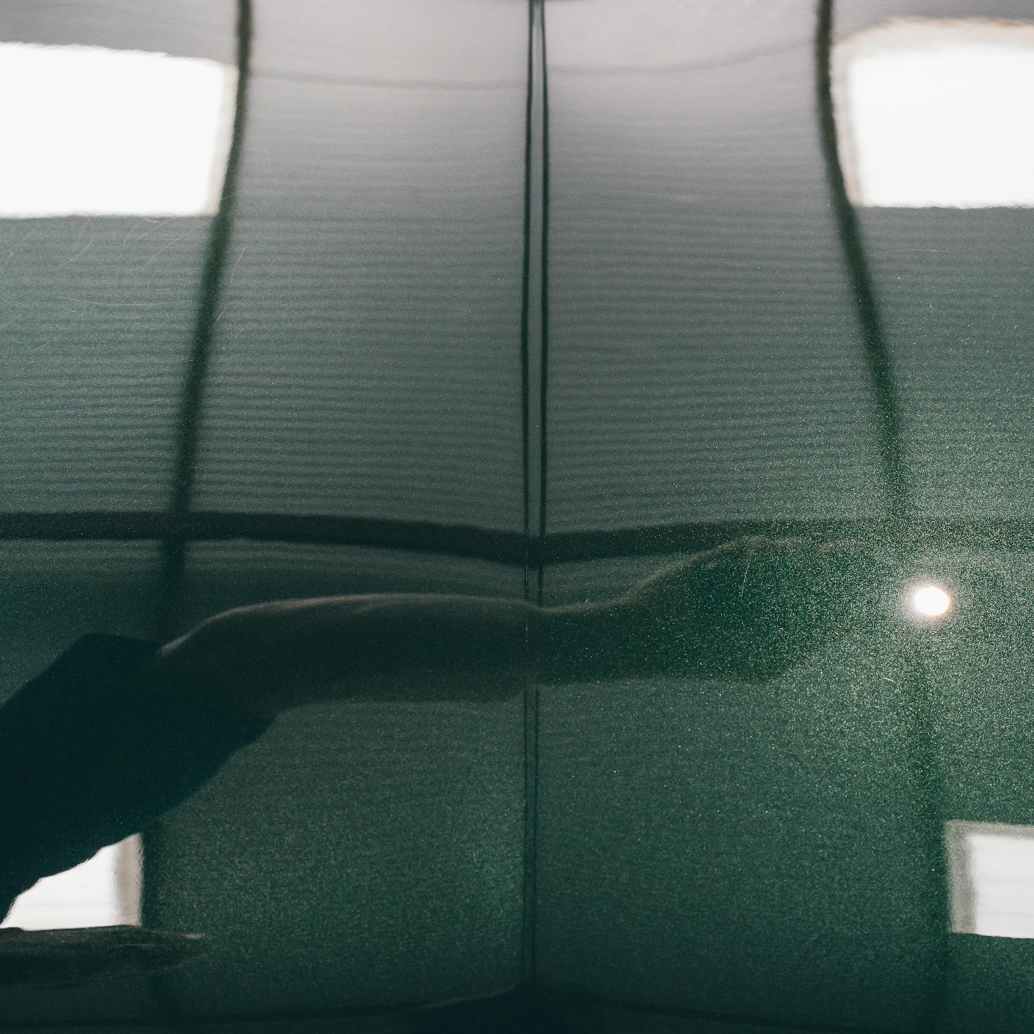 Close-up of a green car's surface with a visible scratch.