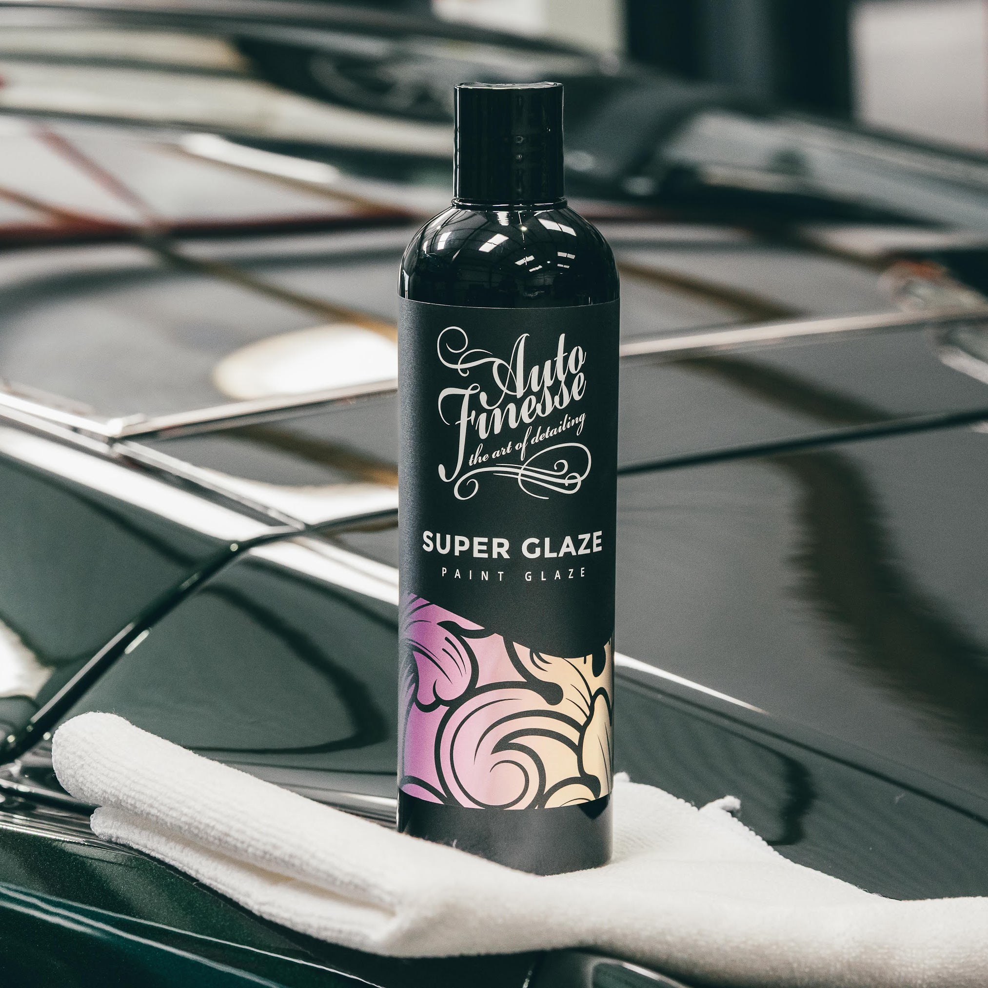 Bottle of Auto Finesse Super Glaze paint glaze on a car surface with a white towel.