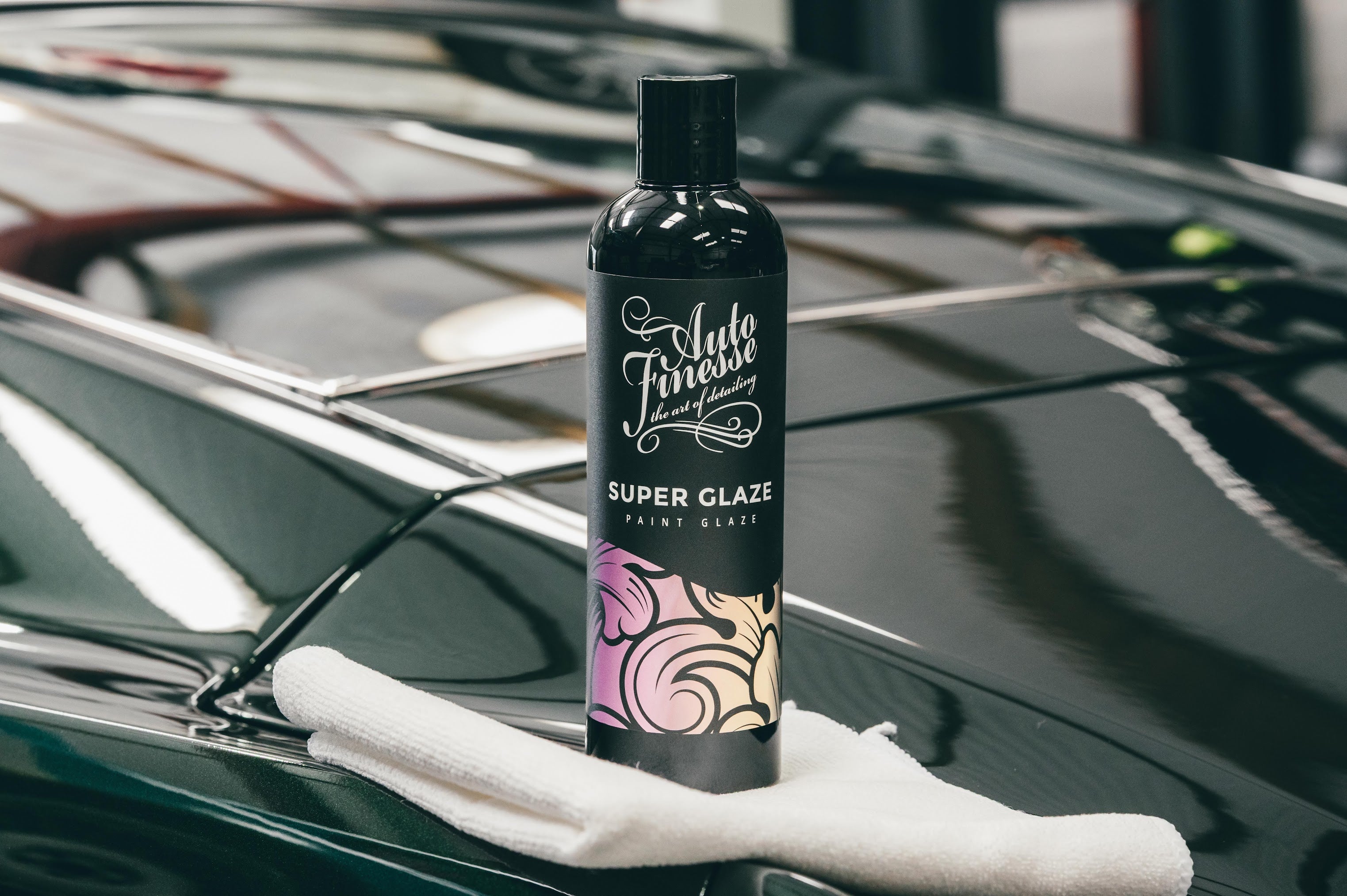 Bottle of Auto Finishing Super Glaze on a car hood with a white towel